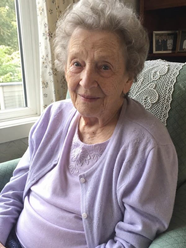 Photo of a woman in her eighties seated in an armchair beside a window