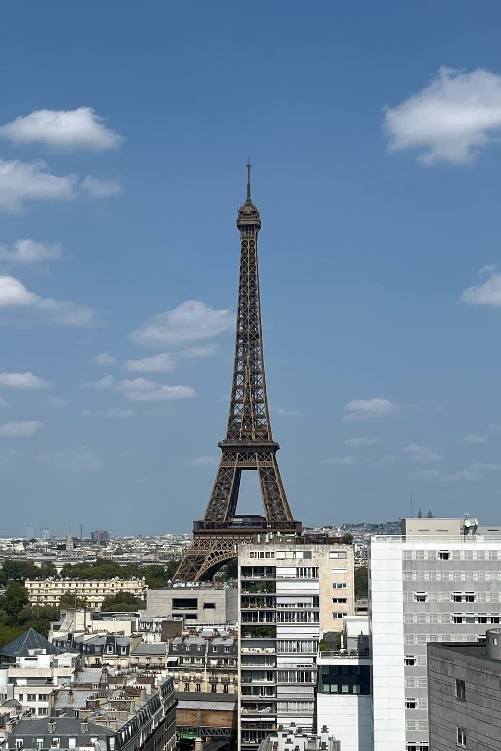 Photograph of the Eiffel Tower above Paris rooftops on a clear day