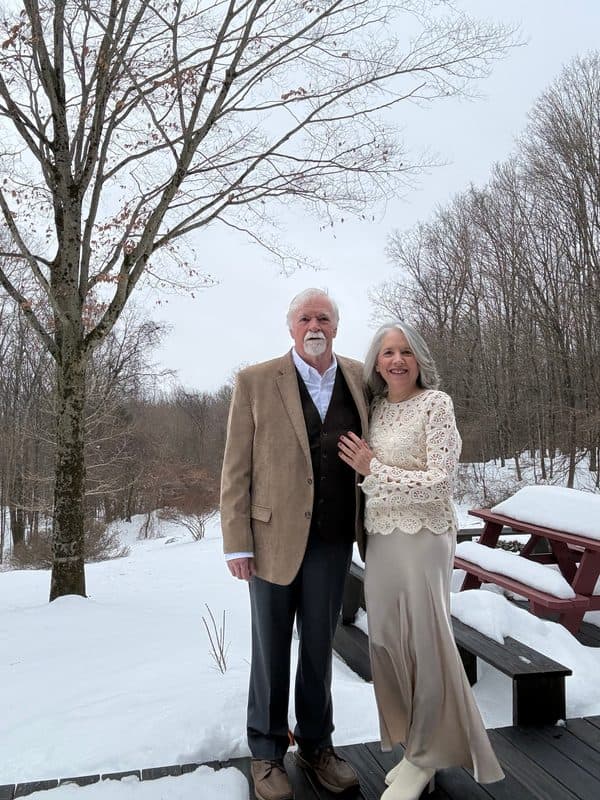 Photo of an older couple standing together in the snow, dressed for an occasion